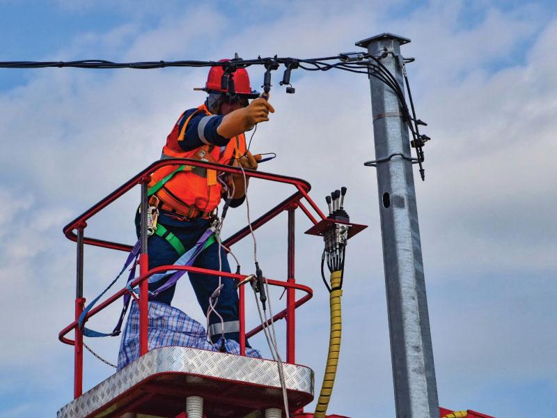 Lineman working on overhead cables from a bucket lift