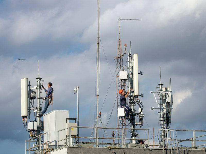 Technicians installing sector antennas on a rooftop telecom site